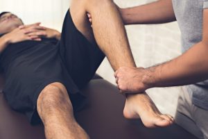 Therapist Treating Injured Leg Athlete Male Patient Clinic Min